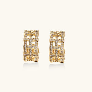 Gold-plated geometric hoop earrings with basket-weave lattice design and pavé crystal accents on cream background