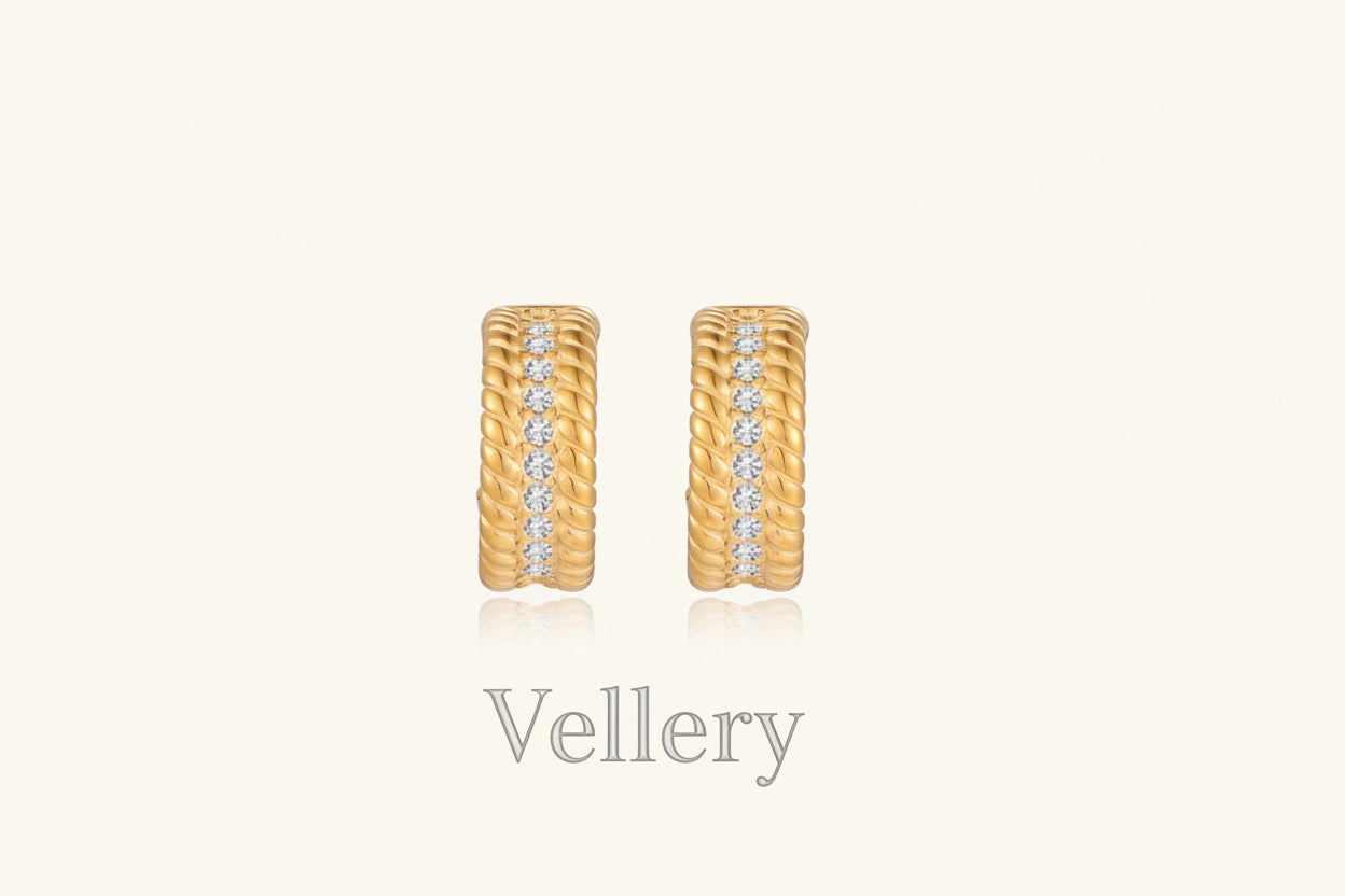 Textured gold huggie hoop earrings with raised ribbed rows creating dimensional sculptural design on cream background