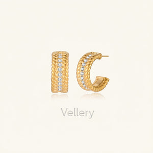 Textured gold huggie hoop earrings with raised ribbed rows creating dimensional sculptural design on cream background