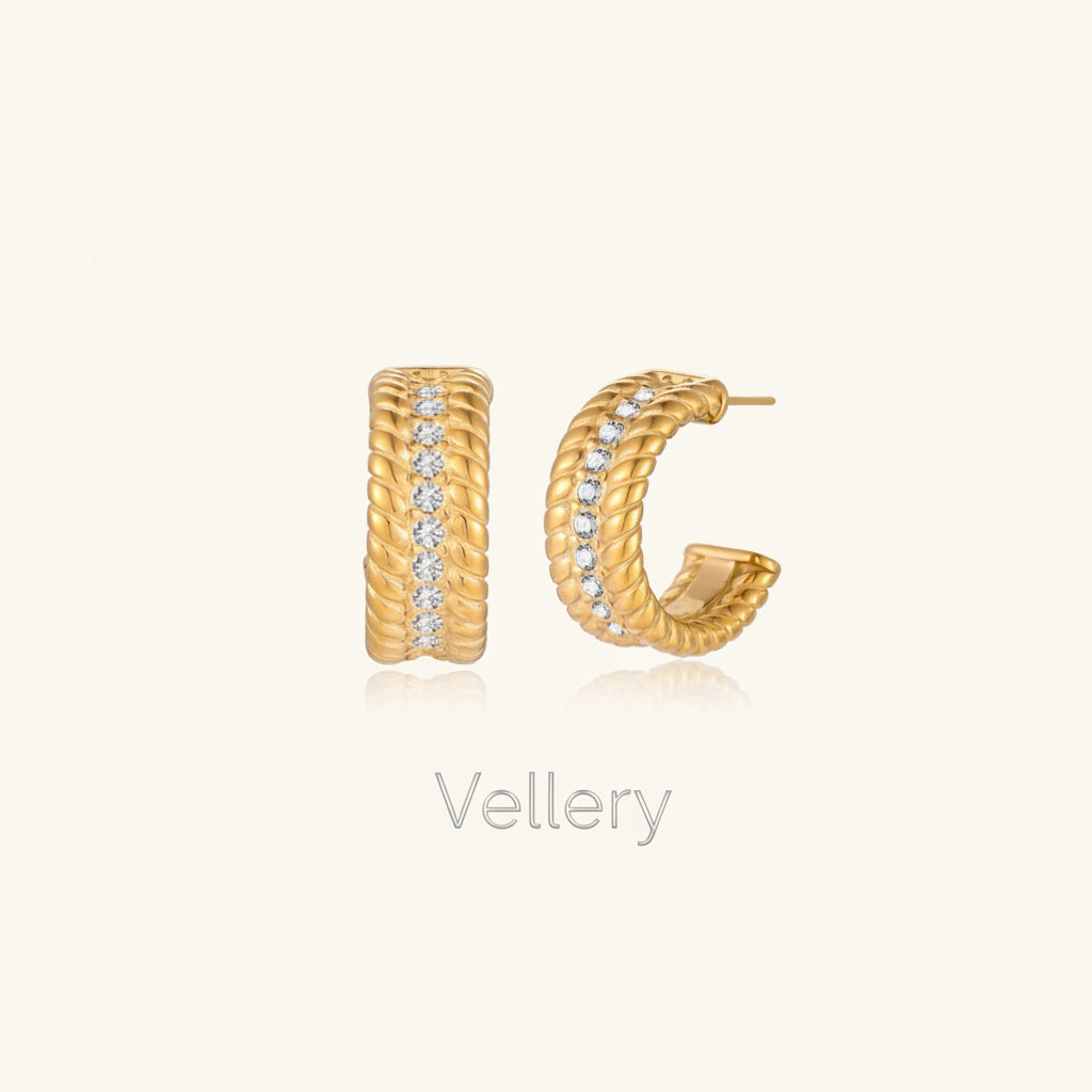 Textured gold huggie hoop earrings with raised ribbed rows creating dimensional sculptural design on cream background