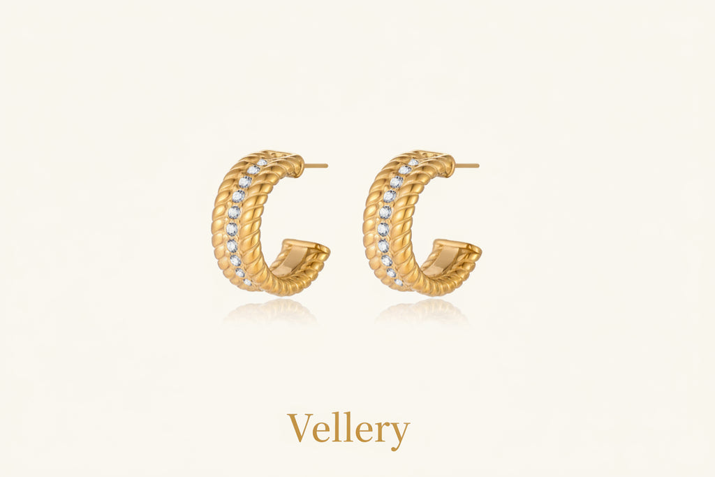 Textured gold huggie hoop earrings with raised ribbed rows creating dimensional sculptural design on cream background